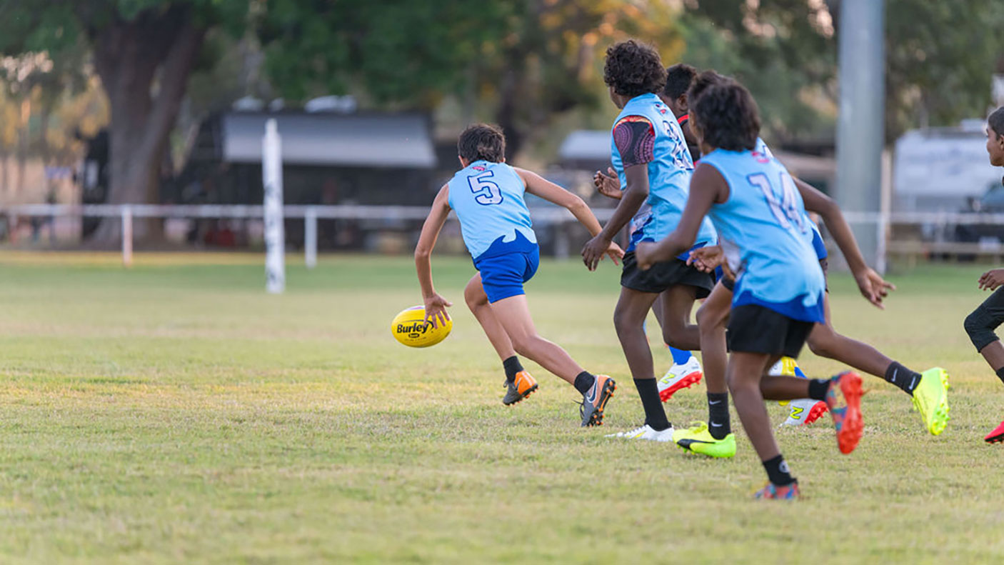 Children in action during a football game in Kununurra