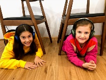 Two girls laying on a wooden floor.