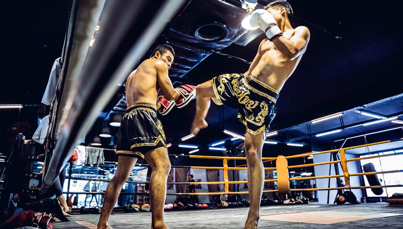 Two mauythai fighters in action in a boxing ring.