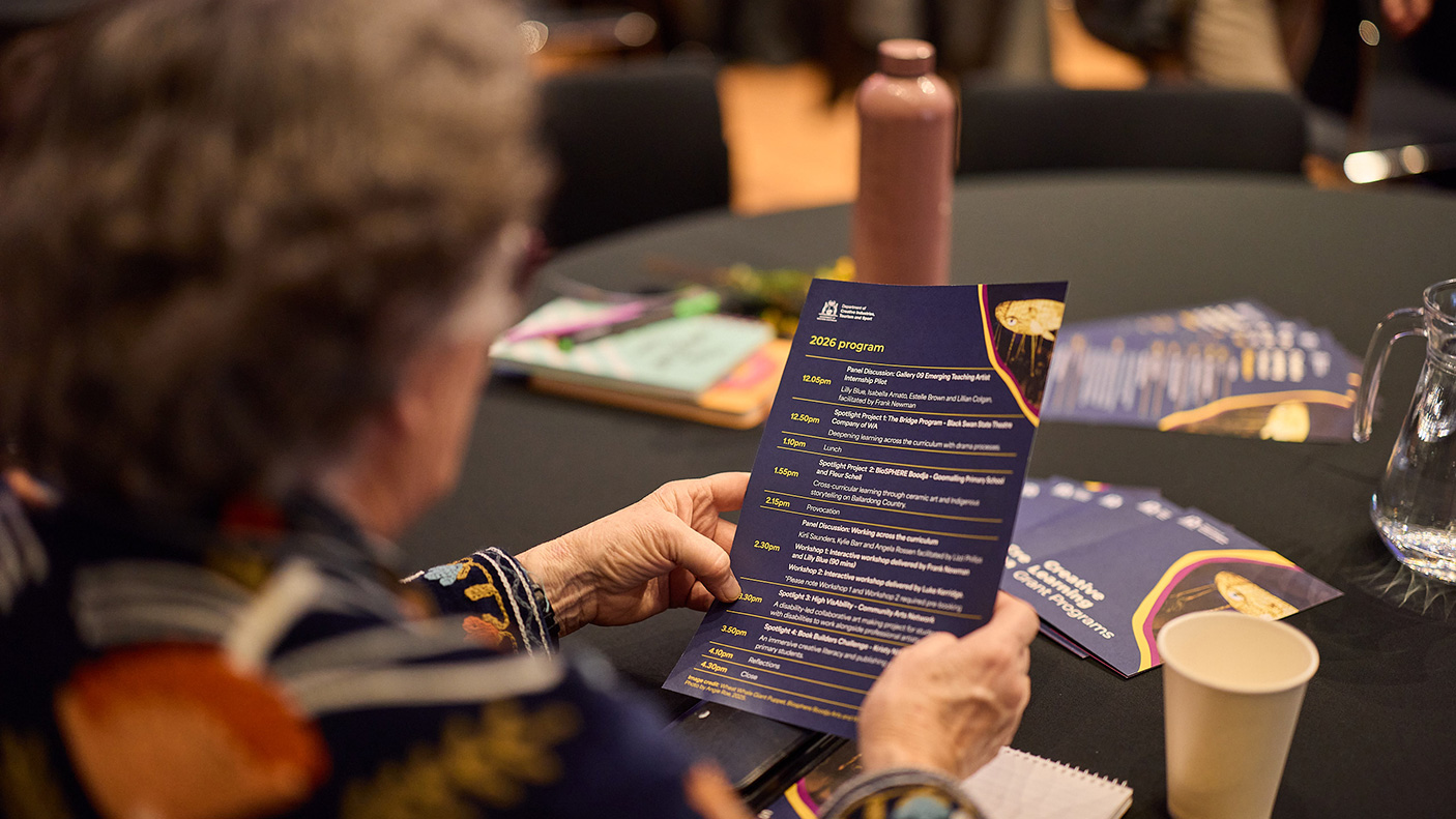 A close up of a person reading the program at the Creative Learning Showcase 