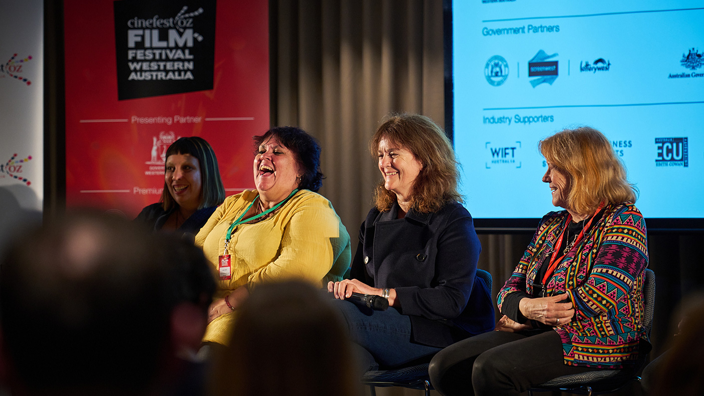 4 people on the stage at a conference.