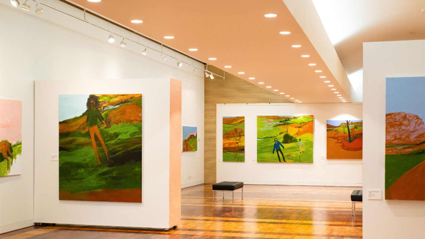 An exhibition space in an art gallery with paintings hanging on the walls