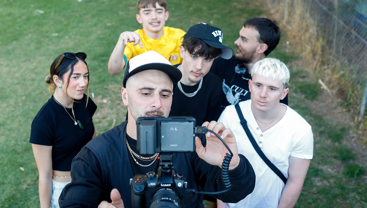A group of young people stand behind a camera.