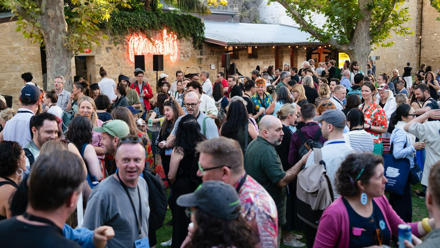 A large group of conference attendees network in an outdoor courtyard
