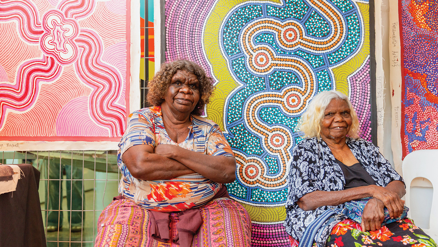 2 artist sit in front of their dot-style paintings