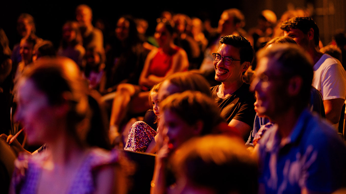 an audience enjoying a creative industries performance in a darkened theatre.