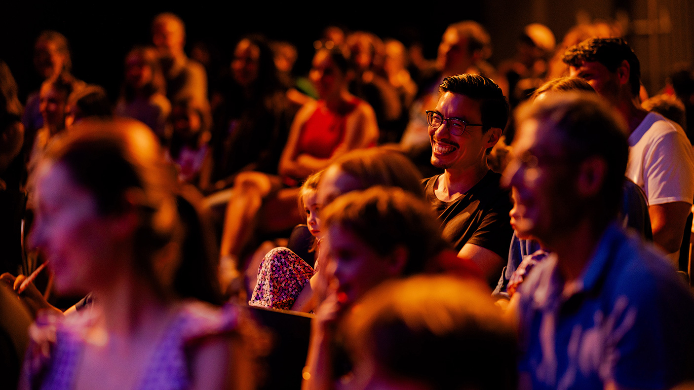 An audience laughing and enjoying themselves in a theatre.