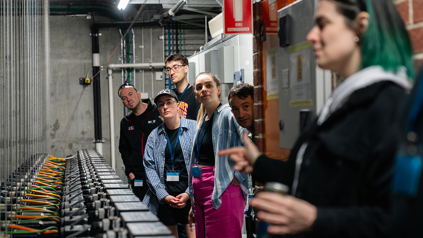 A small groop of people observe a worked back of stage.