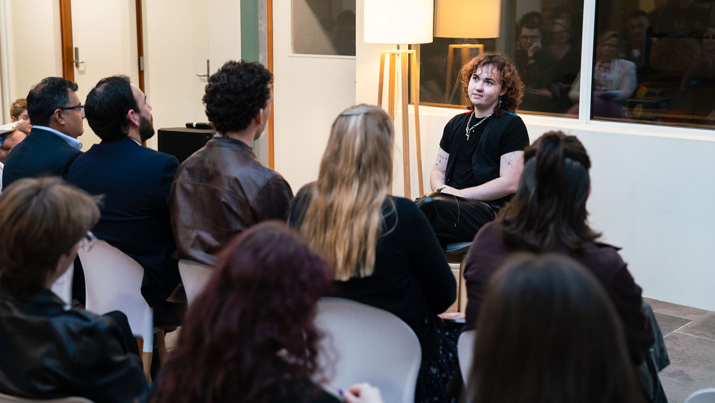 a group of people sitting, listening to a speaker