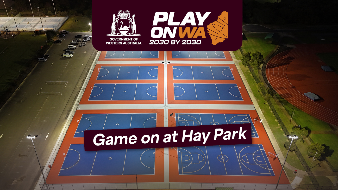 erial view of multiple blue and orange sports courts at night, with a banner overlay at the top reading 'PLAY ON WA 2030 BY 2030' and 'Game on at Hay Park.'