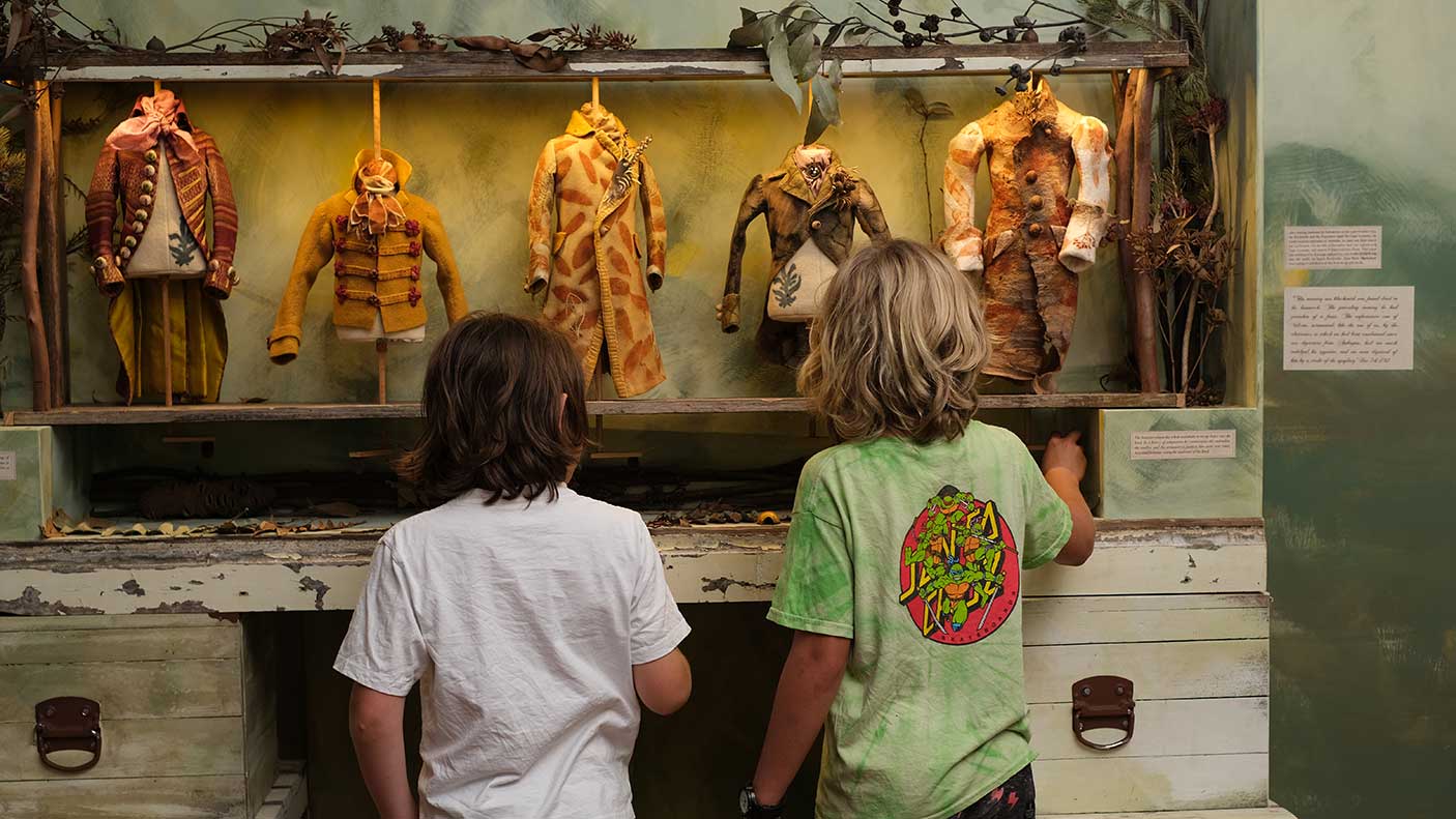 Two boys looking at an exhibit of old puppet clothes