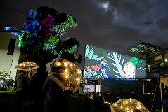 A projection on a screen at night amongst building.s.