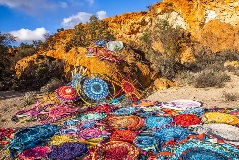 Woven rugs placed on rocks and ground.