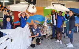 A group of students and teachers holding some large sized puppets.