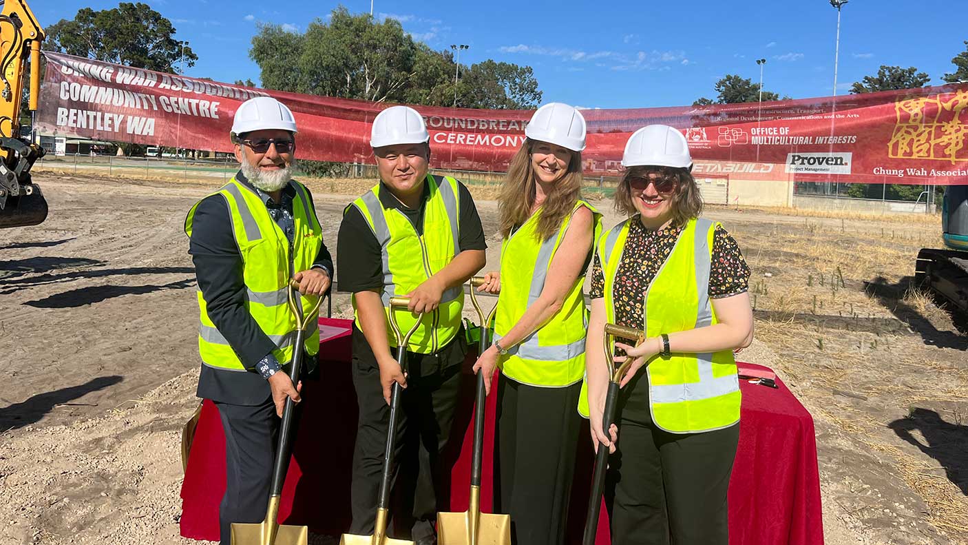 4 people in safety attire holding shovels at the construction site