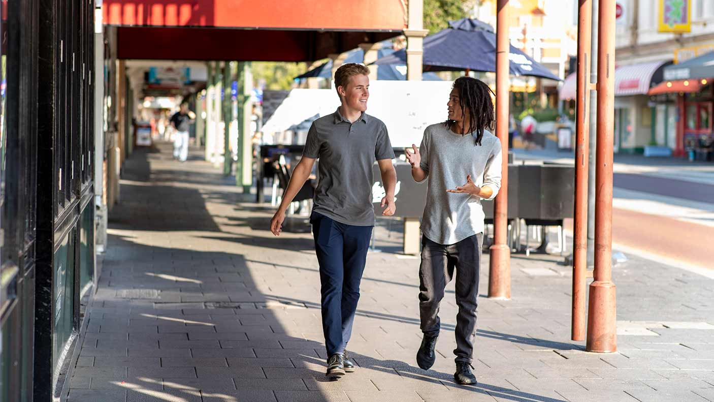 Two men talking and walking down a main street in a town