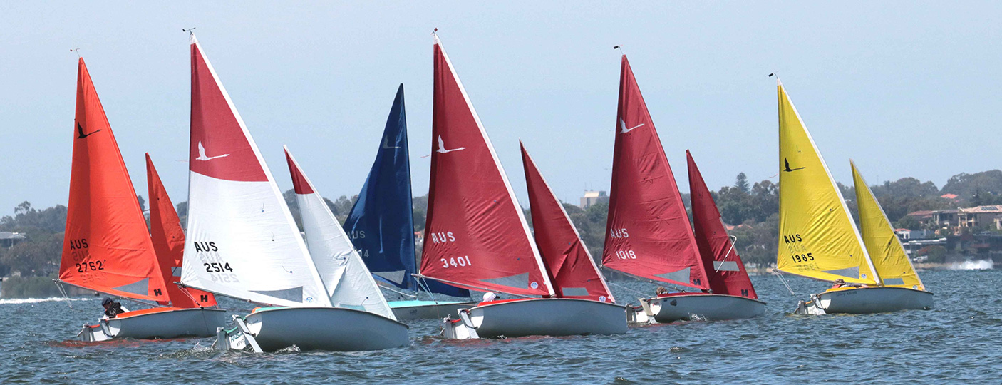 a fleet of small sailing boats on the water during a sailing competition