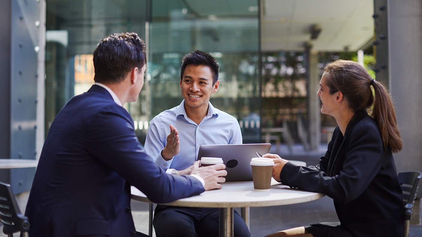 3 people in business/officce attire have a meeting over a coffee.