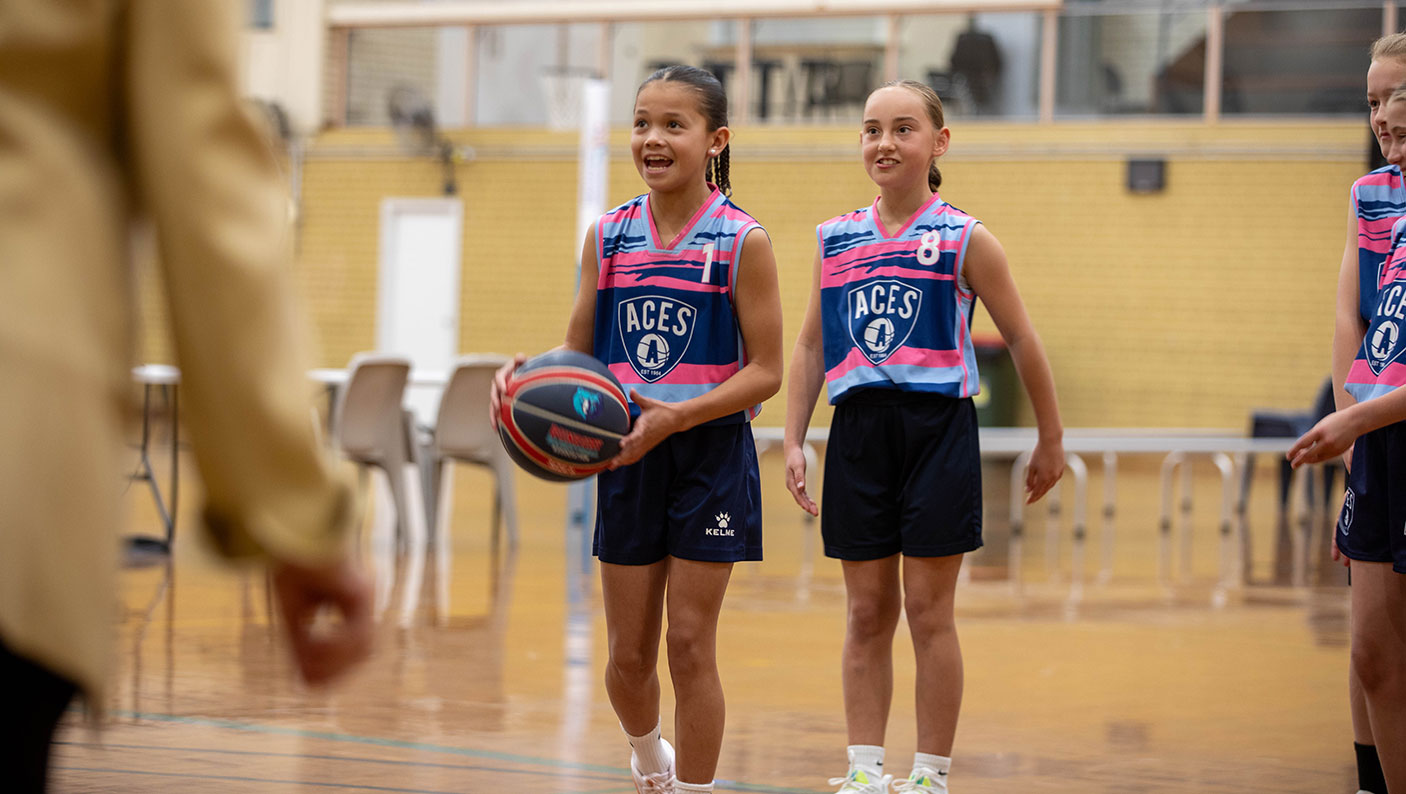 two young female basketball players on an indoor basketball court