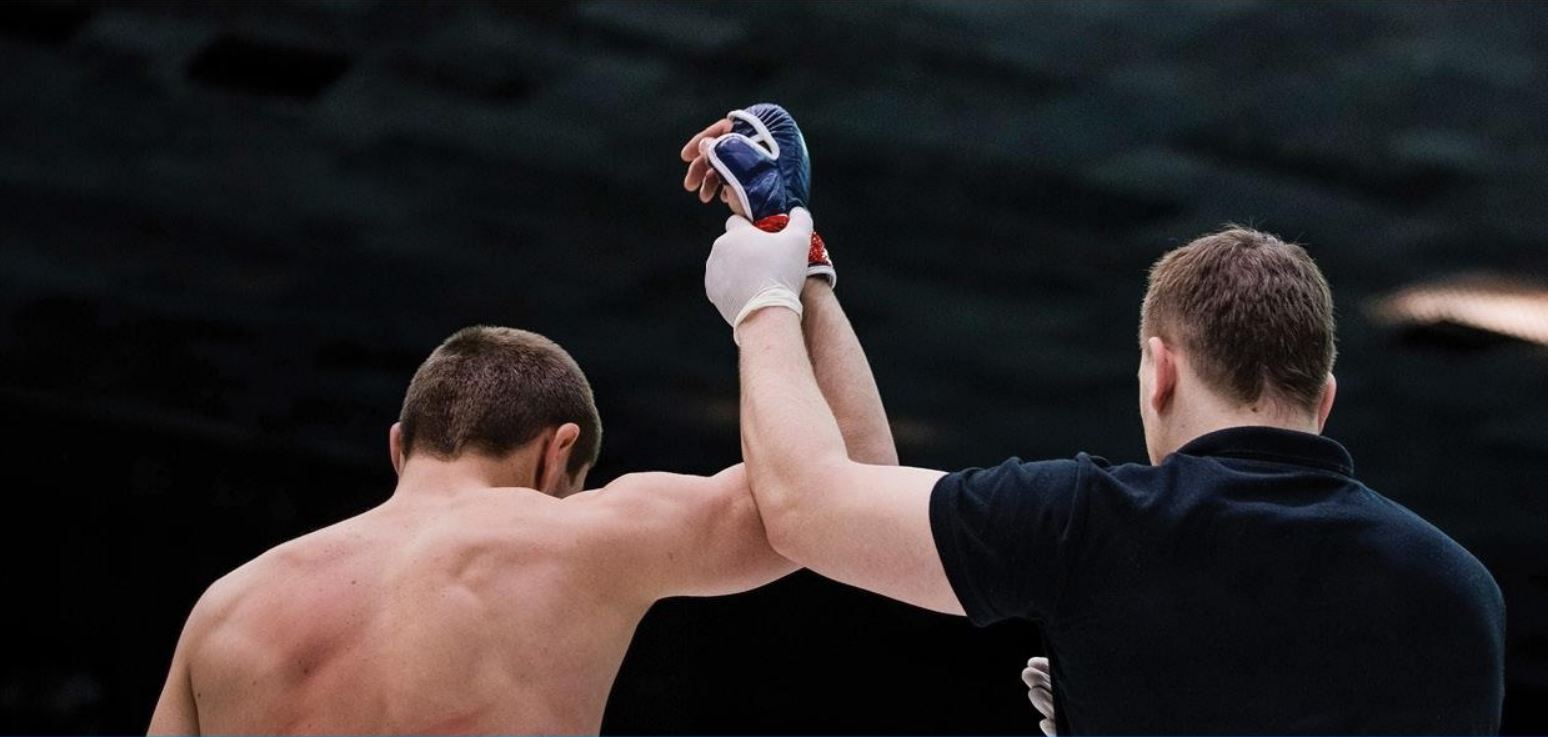 Referee holding mixed martial artists arm in the air
