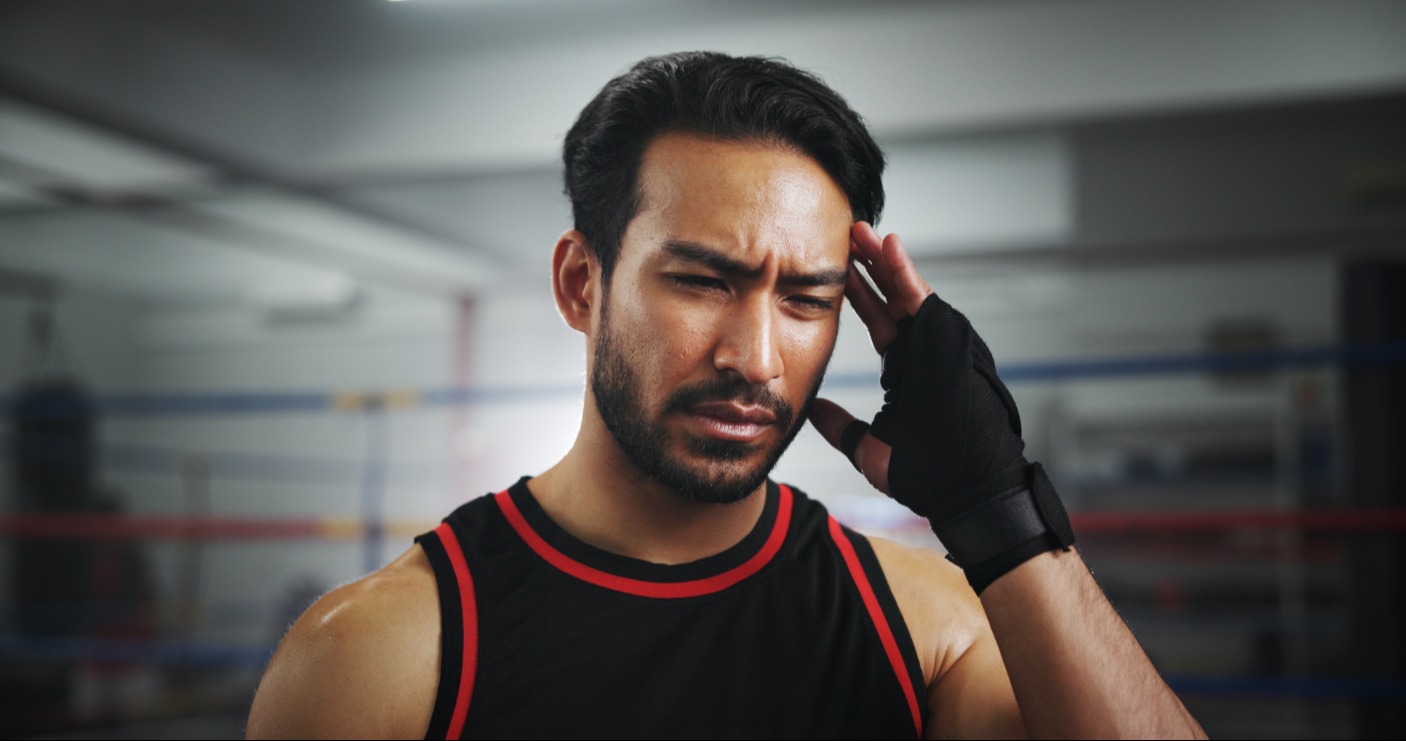 Combat sports athlete showing signs of a headache with hand to side of head - Stock photo
