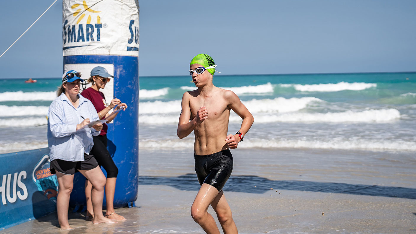 A young man runs out of the surf to cross the finishing line