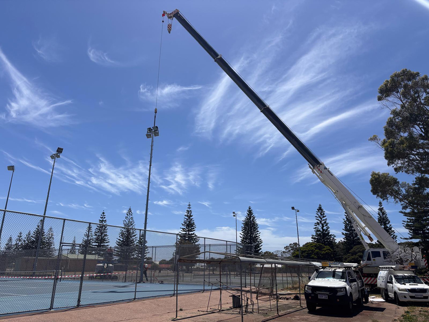 A large crane installing lighting towers at the Esperance Tennis Club