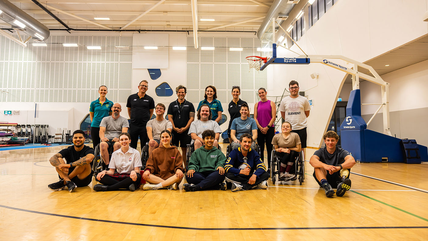 A group of athletes pose for the camera on an indoor netball court