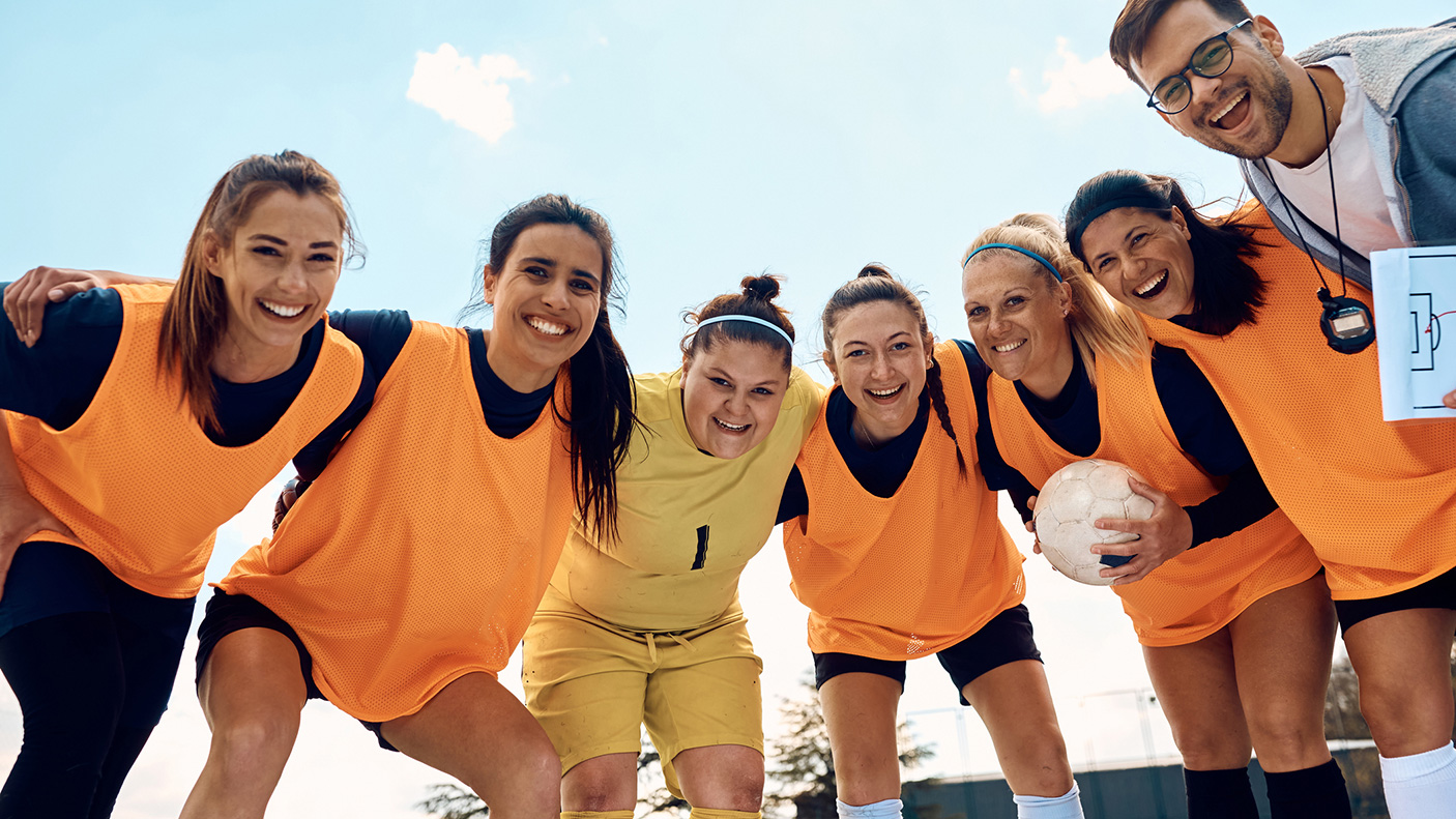 A female sporting team huddle with their coach