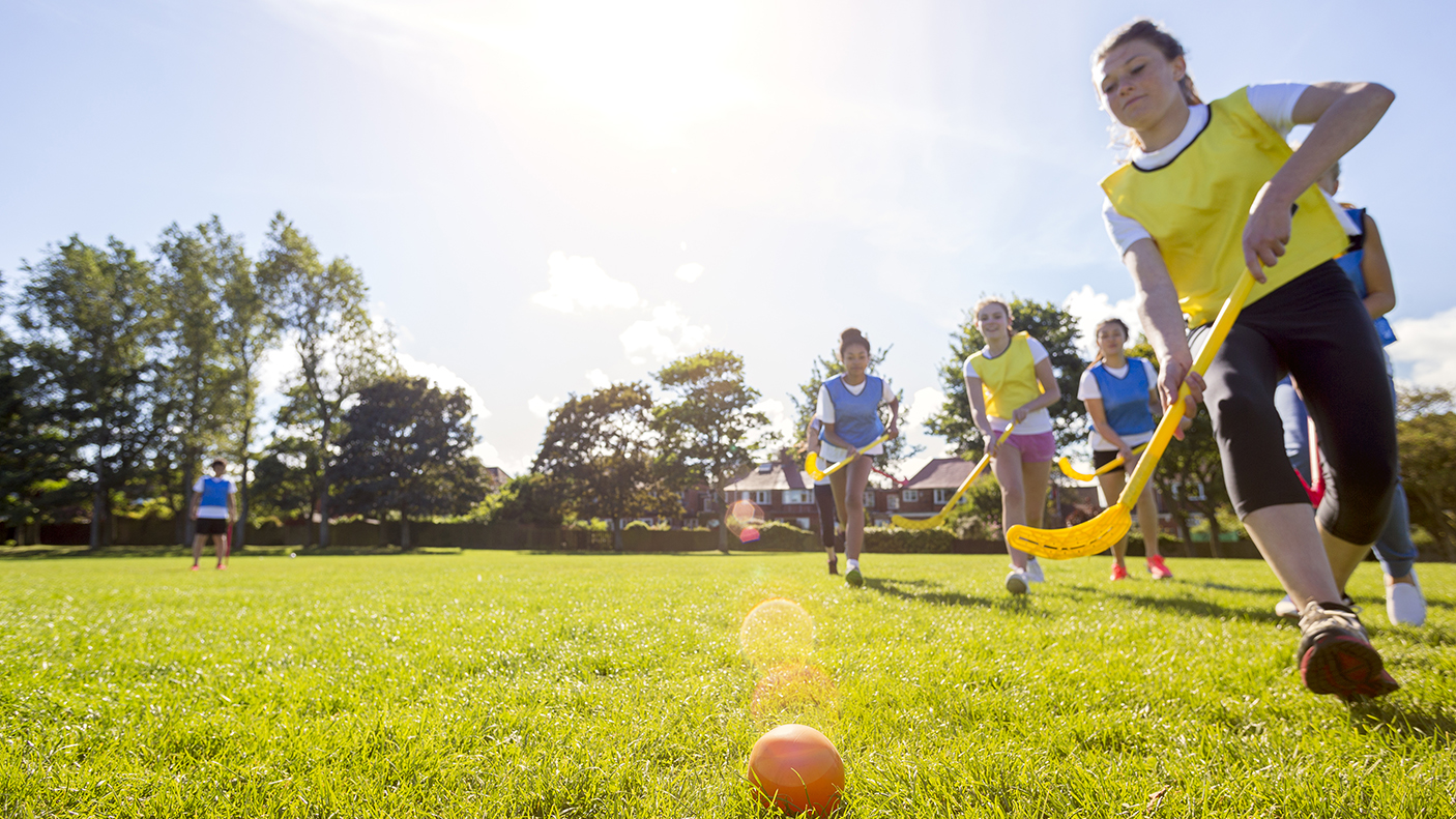 Girls playing field hockey on a grassed field