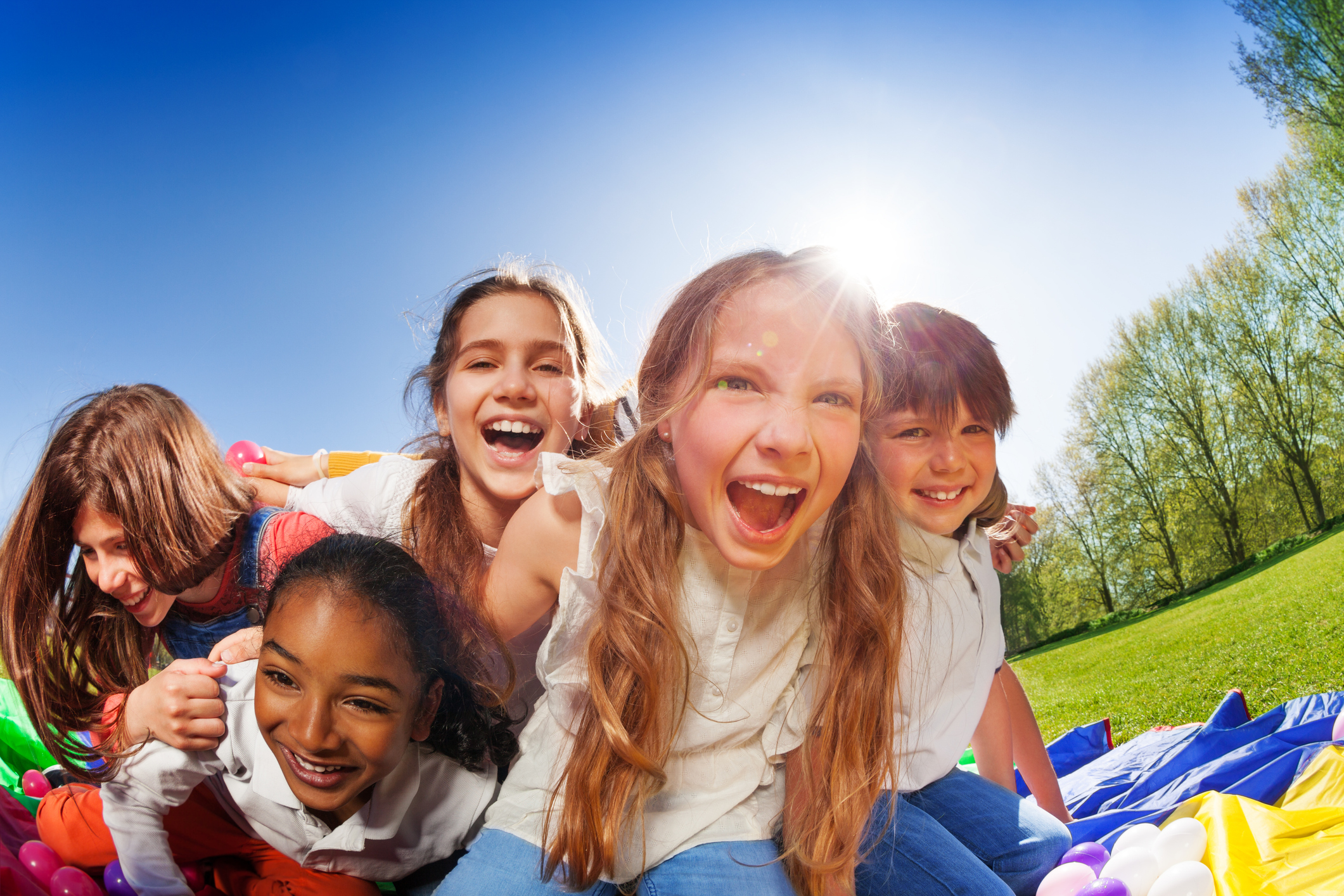 5 school age children laughing and playing outdoors
