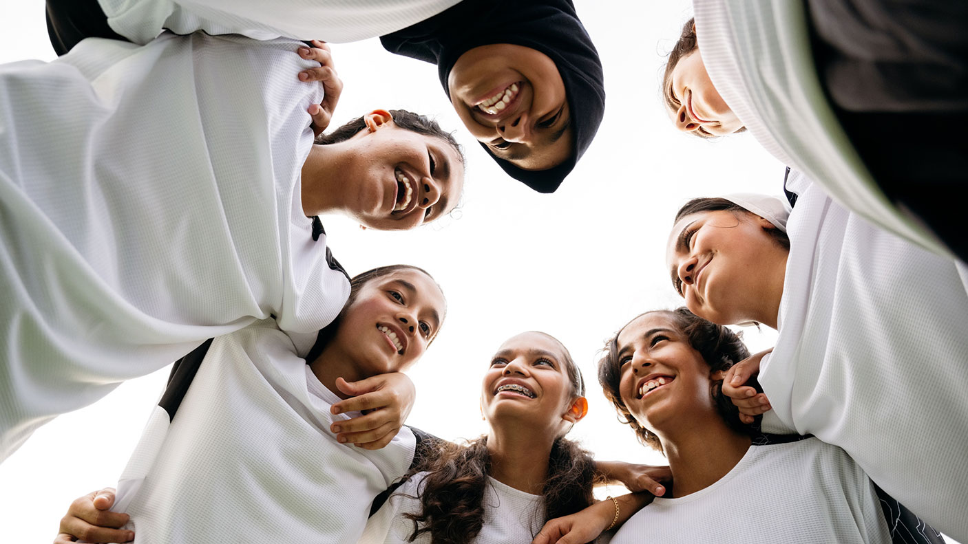 7 girls in sporting team uniform huddle in a circle
