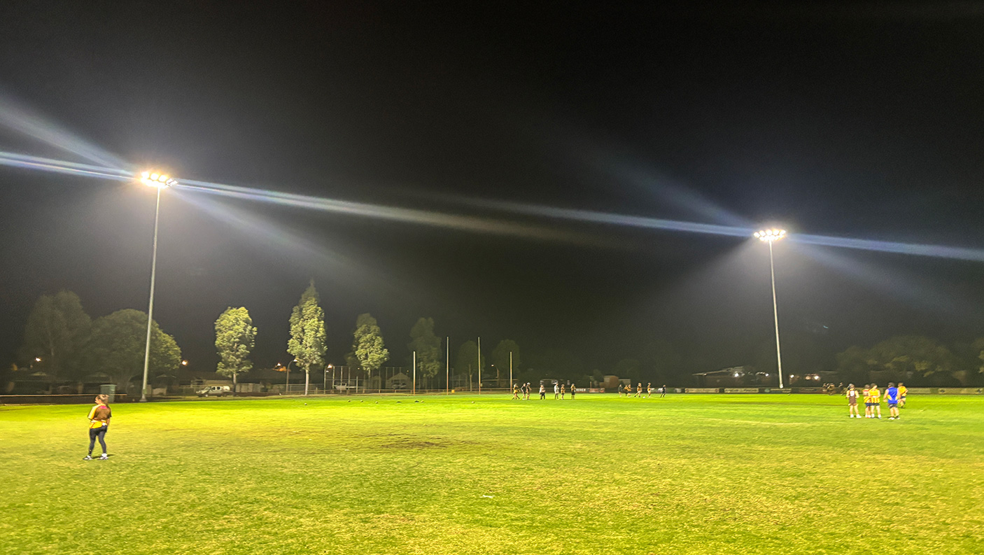 Flood lights lighting up the Glen Huon Reserve while people train on the pitch.