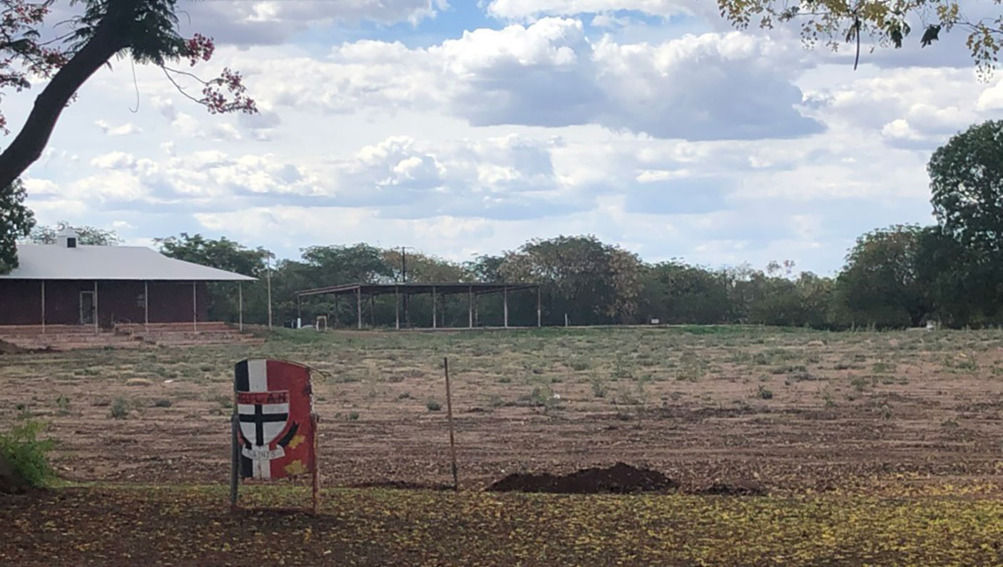 A sporting oval in need or repair, with a few weeks and mostly dirt surface.