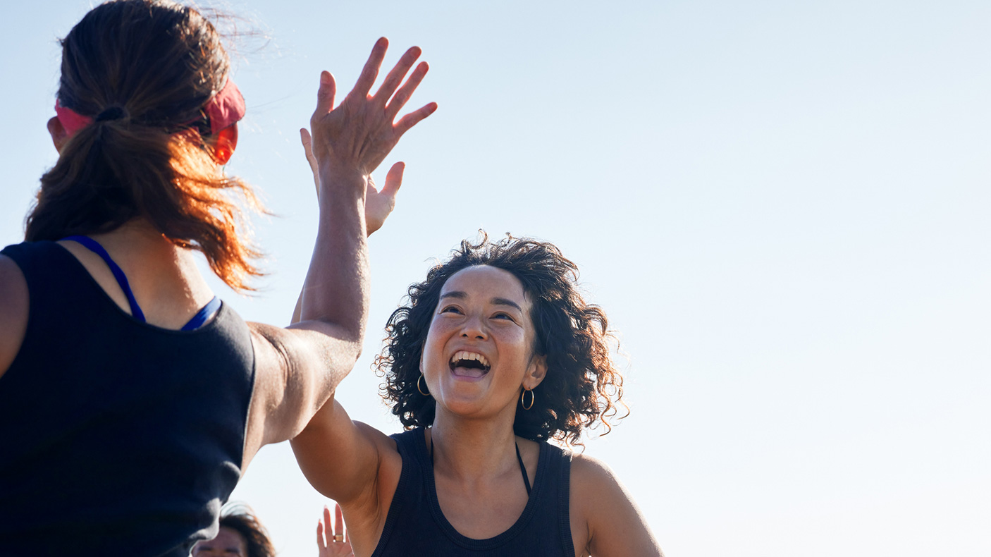 two women in sporting clothes high five each other