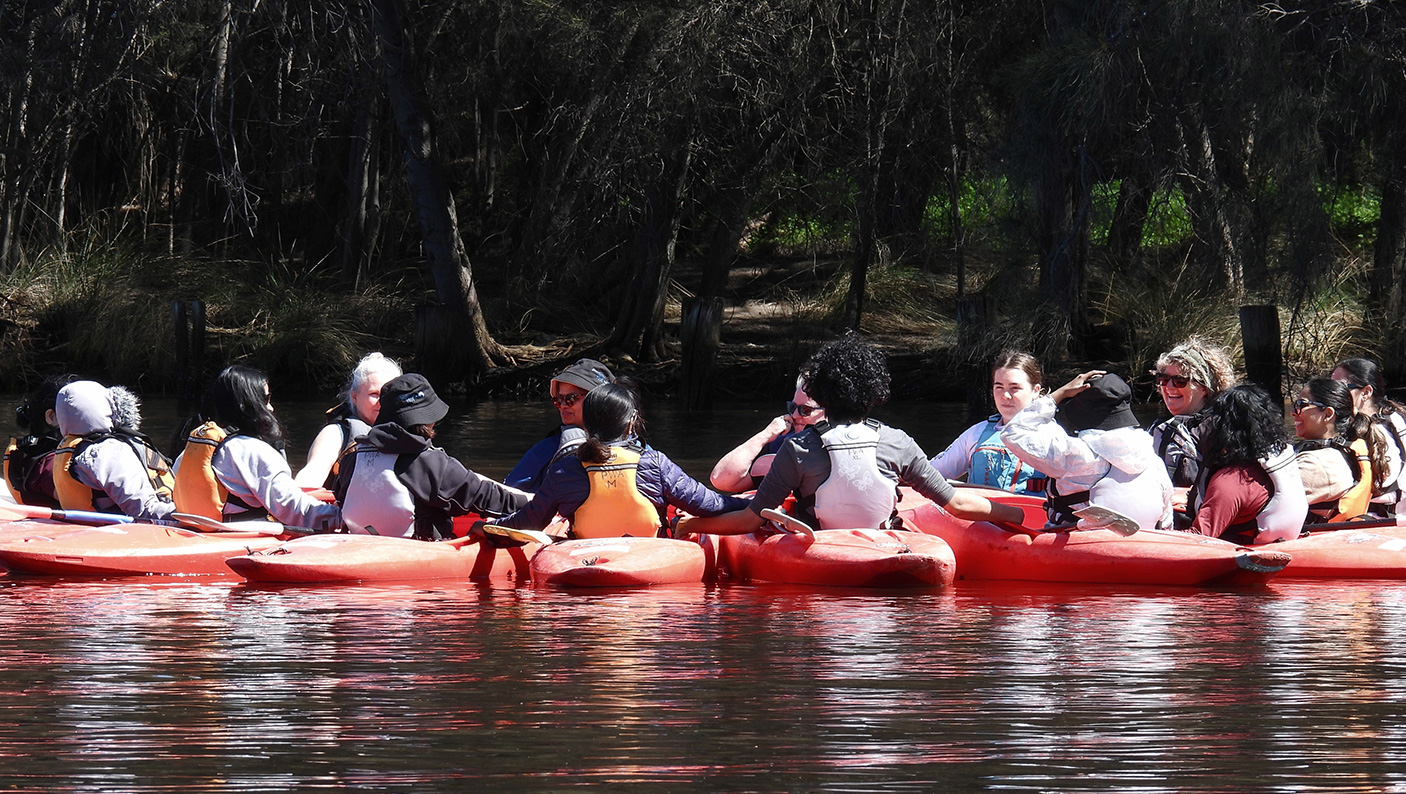 A group of women in kayaks on a calm river