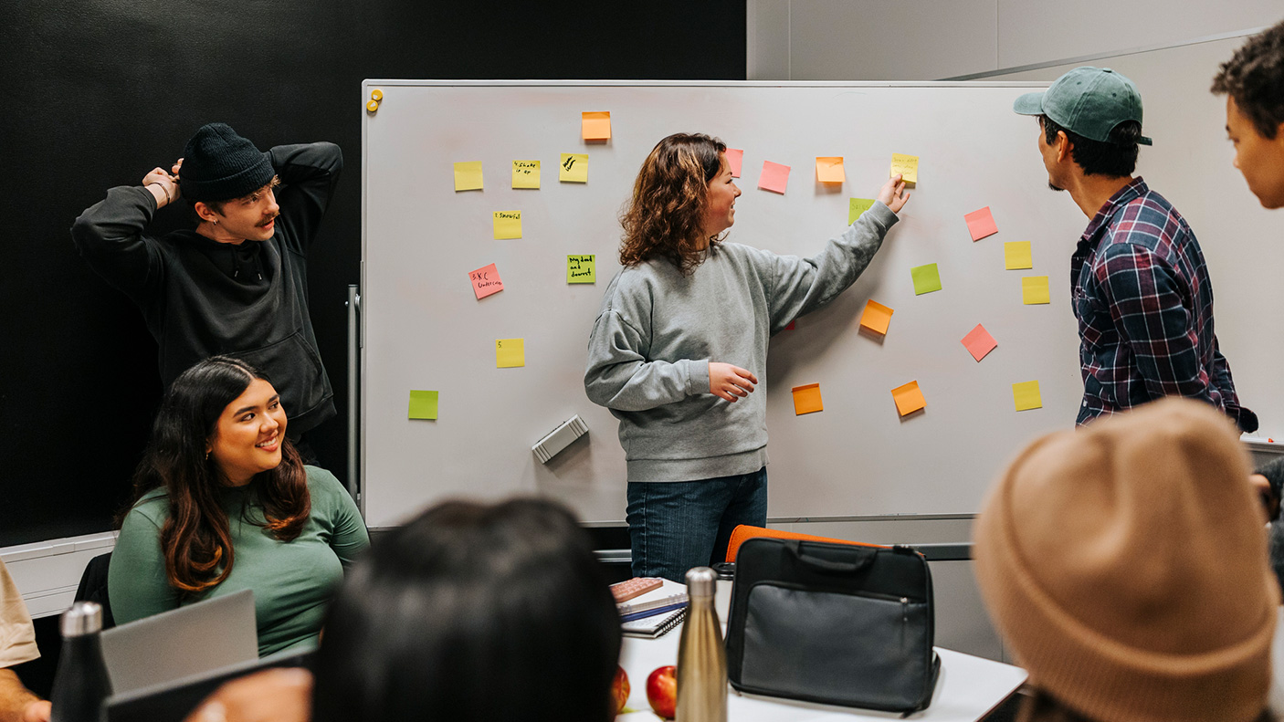 A group of people work with post it notes on a whiteboard