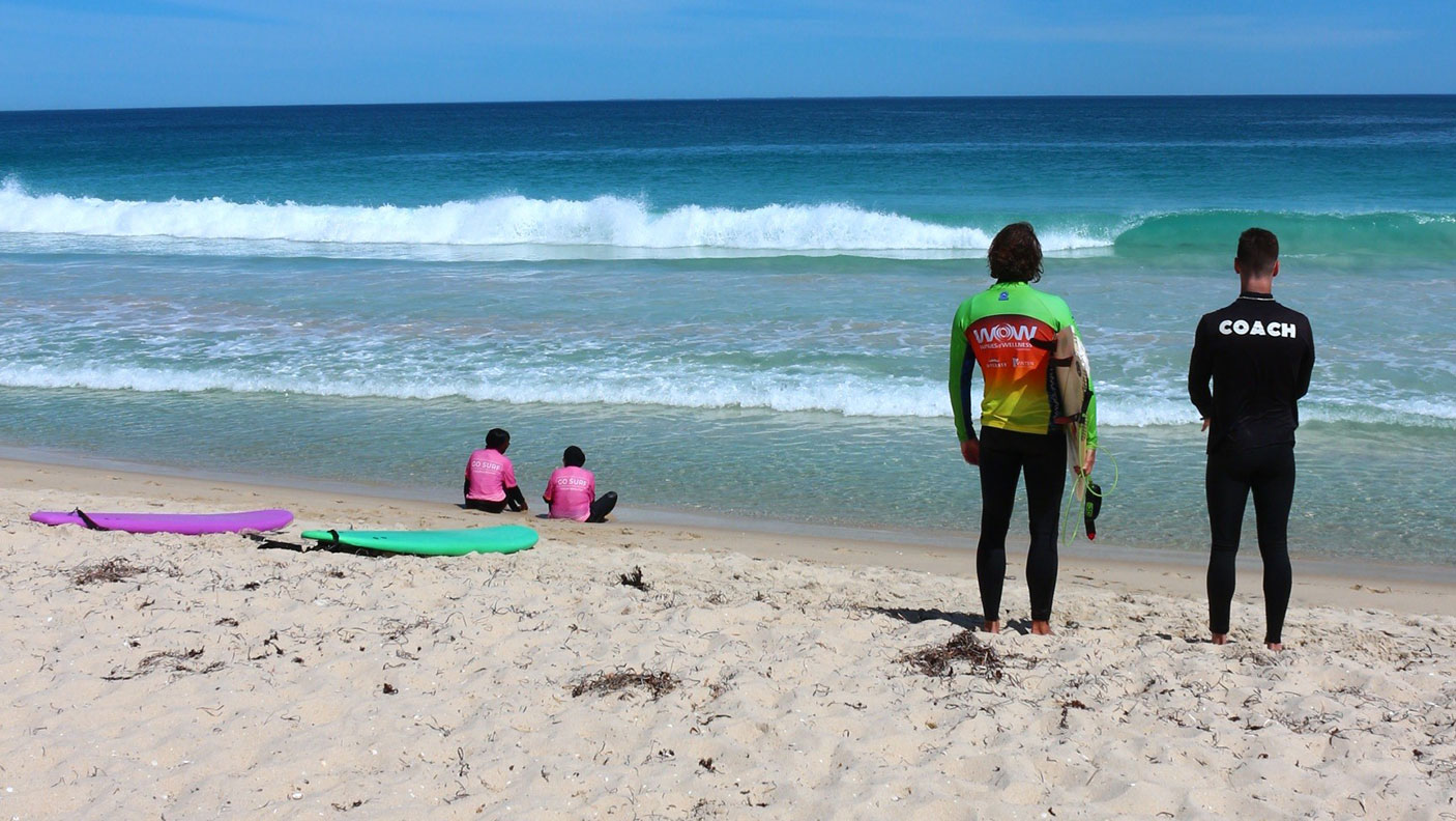 4 people on the beach, with surfboards and in wetsuits