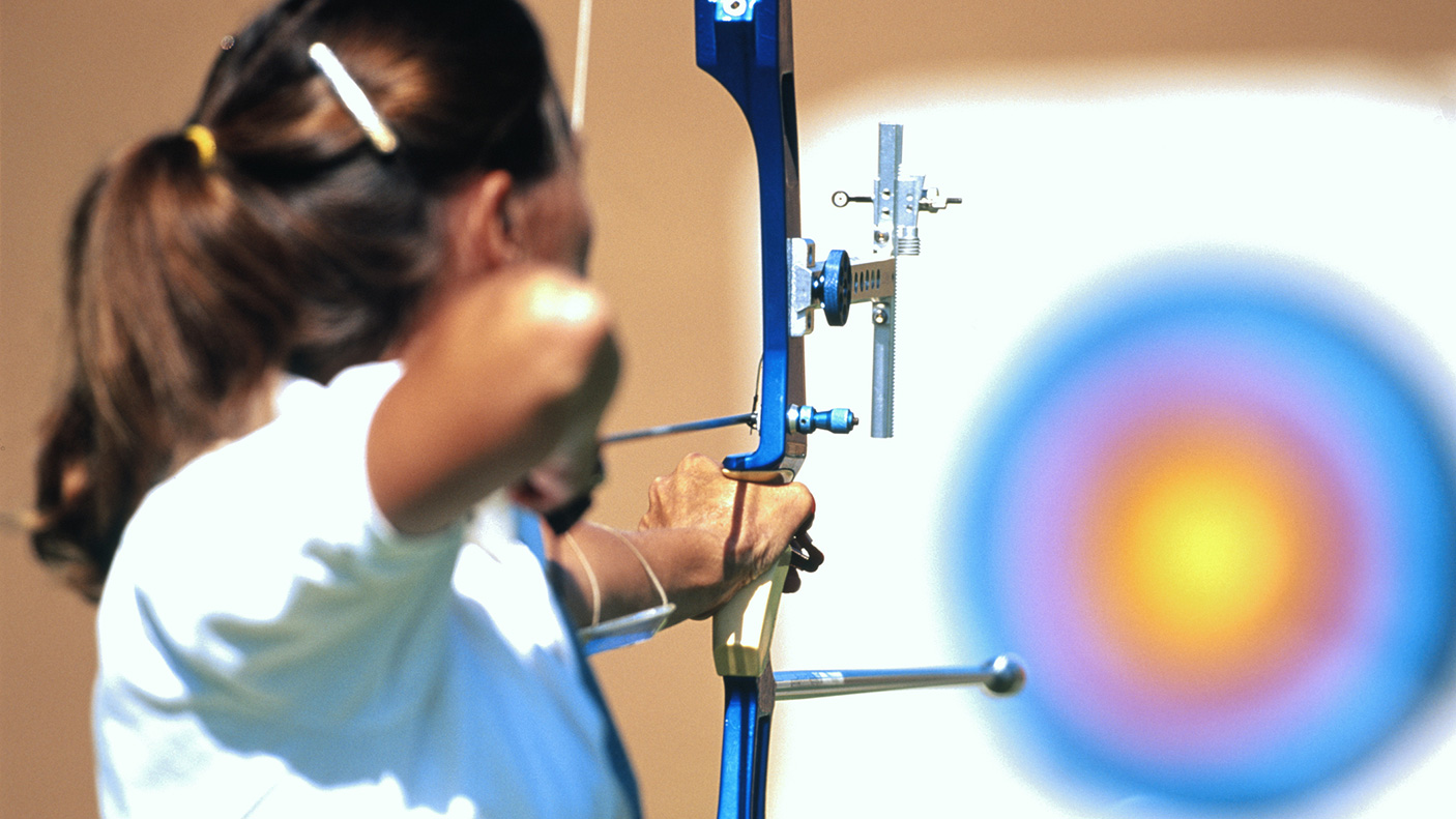 a woman prepares to shoot an arrow at a archery target