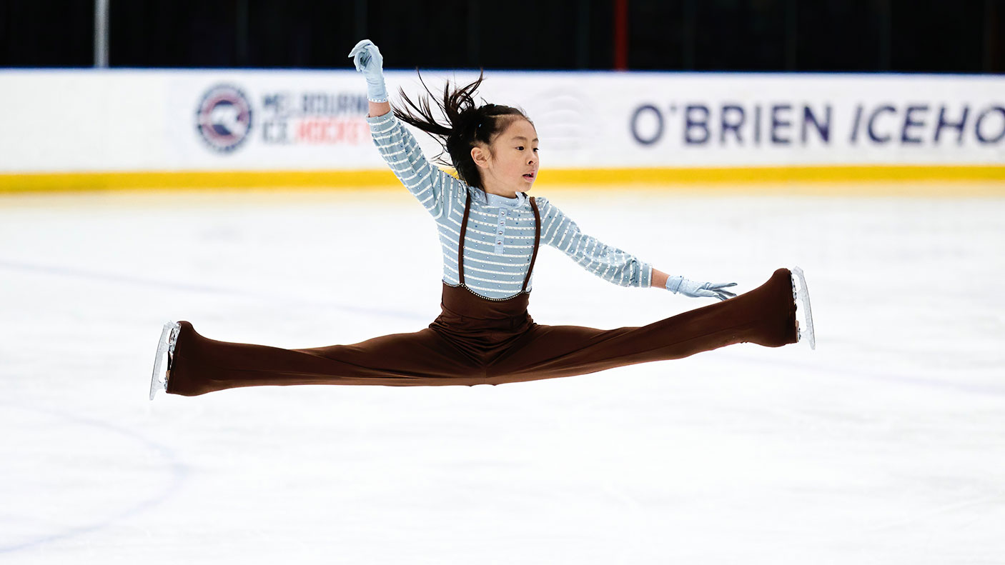 A young ice skater does a leap