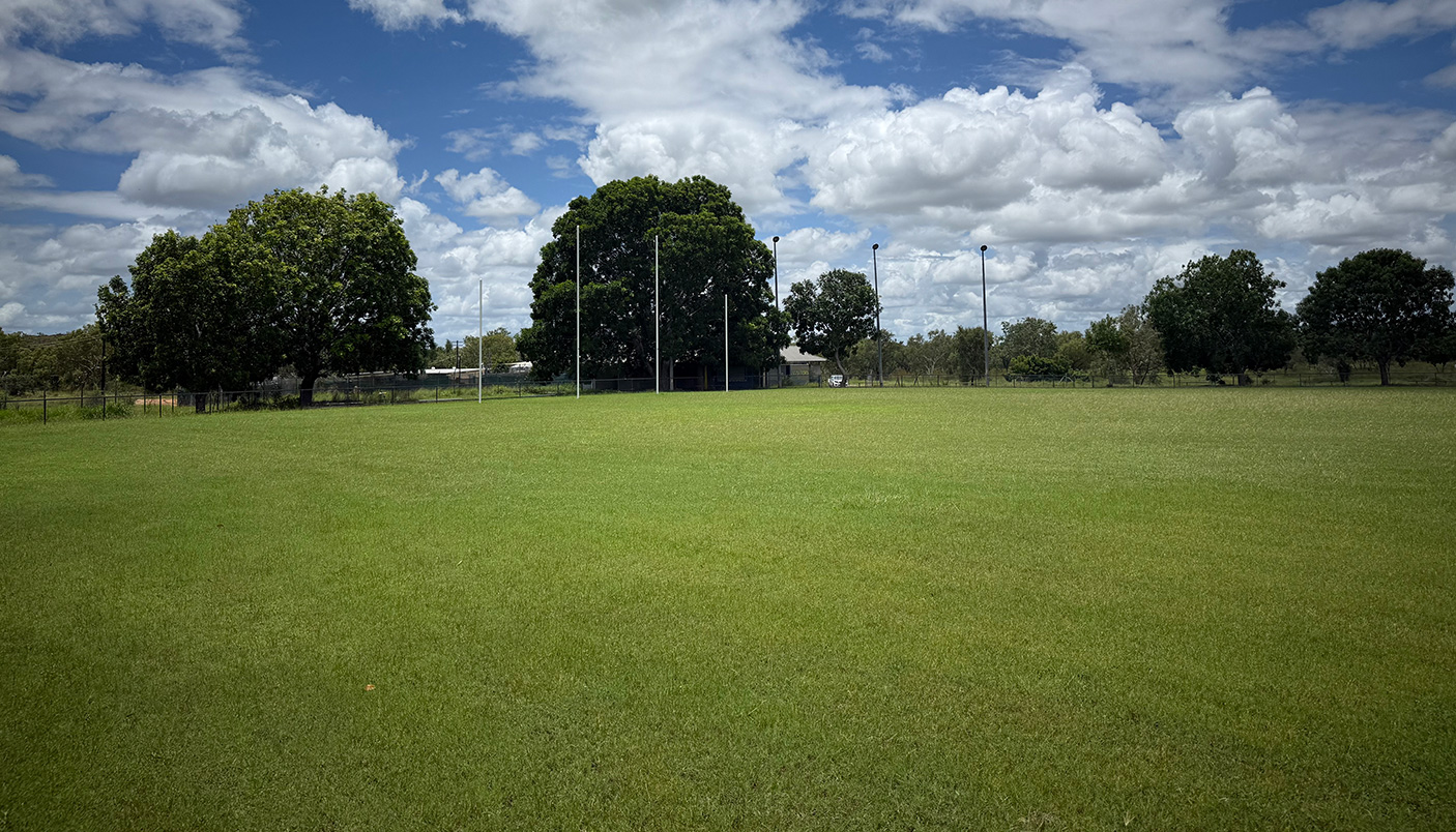 A grassed sporting oval with trees in the background