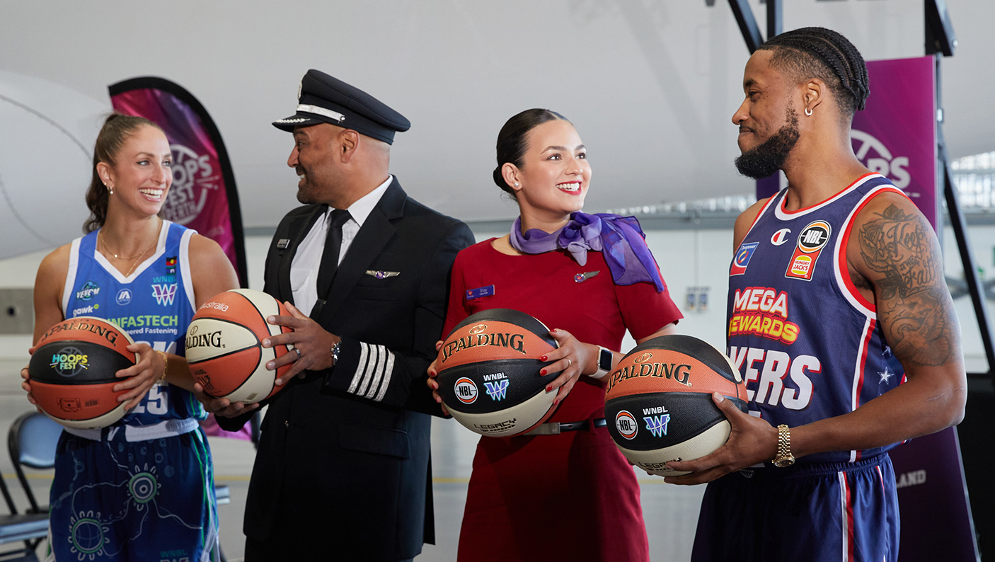 2 professional basketball players, a Virgin Australia pilot and flight attendant pose with basketballs in front of a Virgin Australia aircraft