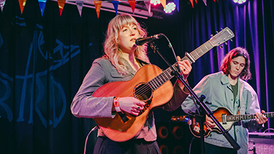Music performers playing guitar and singing on a stage under coloured lights