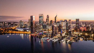 Aerial view of Perth city skyline and waterfront at dusk with lights reflected on the rive