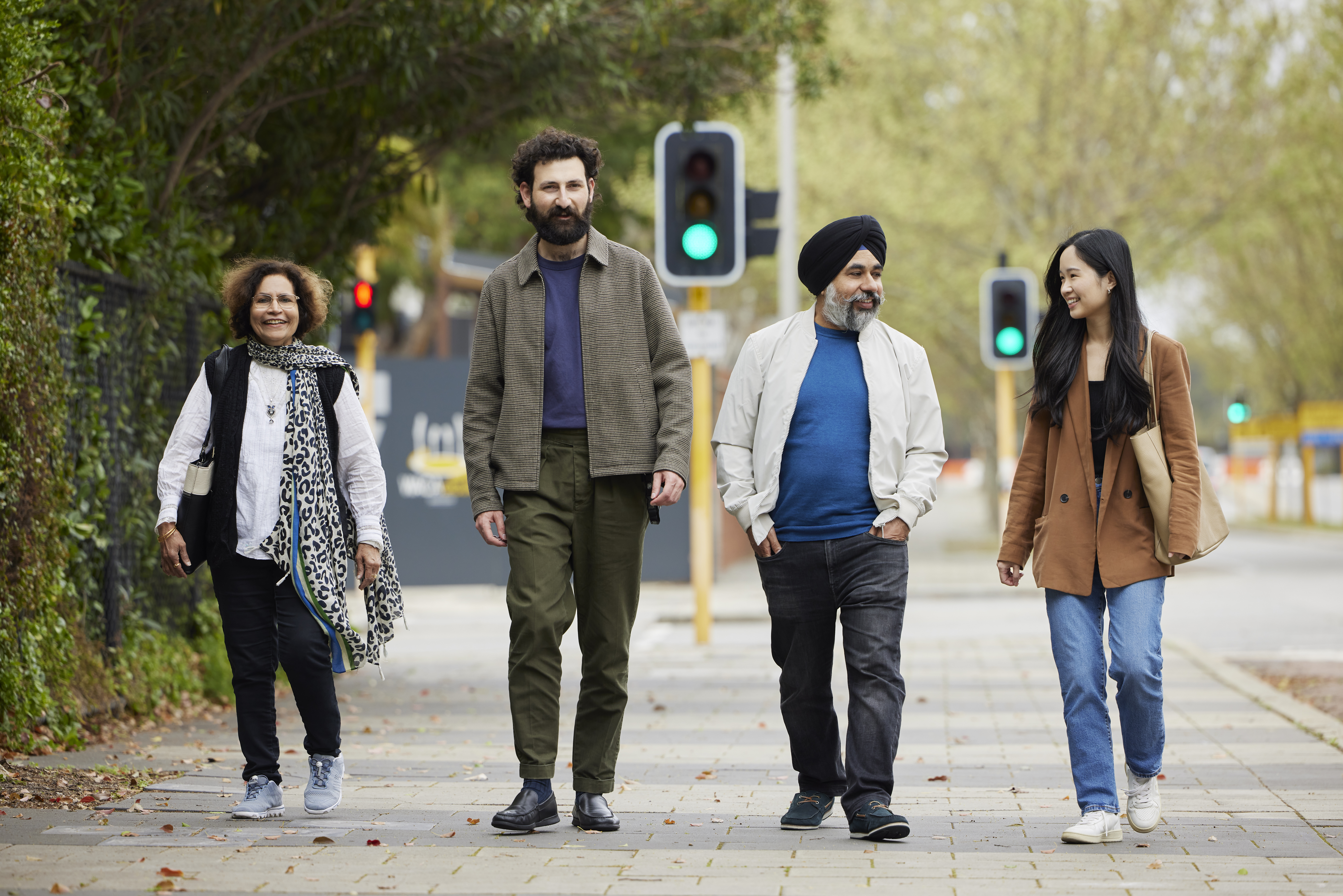 Three senior citizens smiling and walking through a park